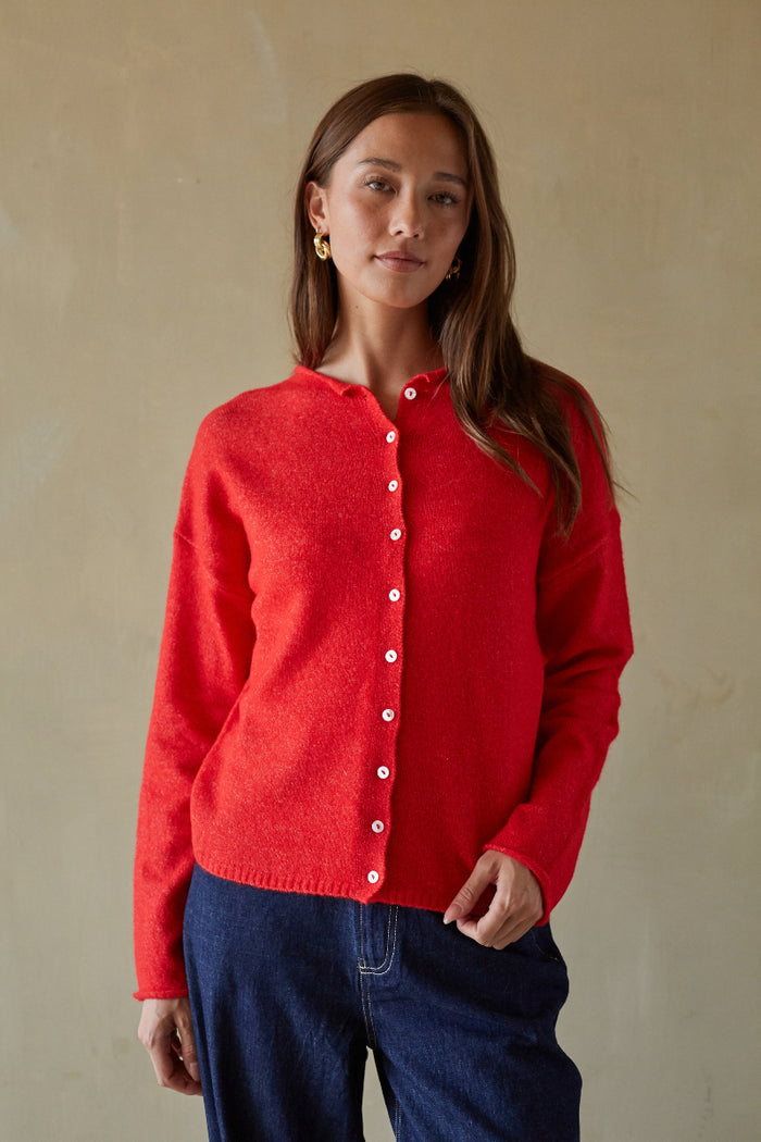 Woman wearing a red cardigan against a beige background