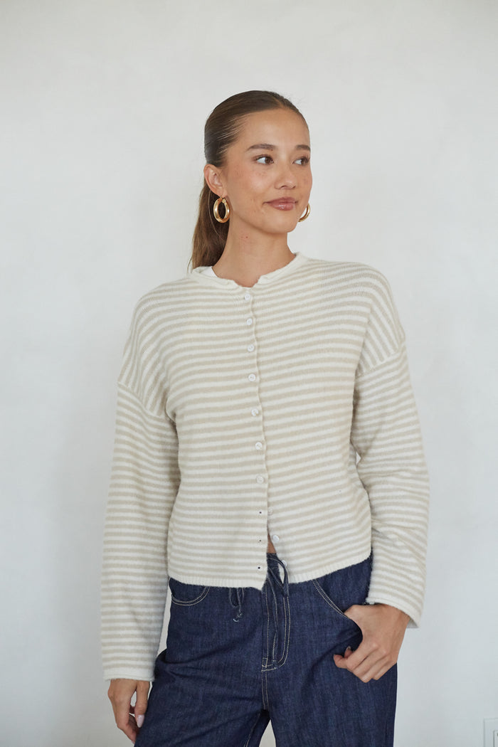 Woman wearing a striped cardigan and blue jeans against a white background