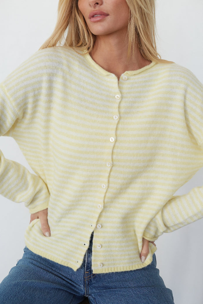 Woman wearing a yellow striped cardigan against a white background