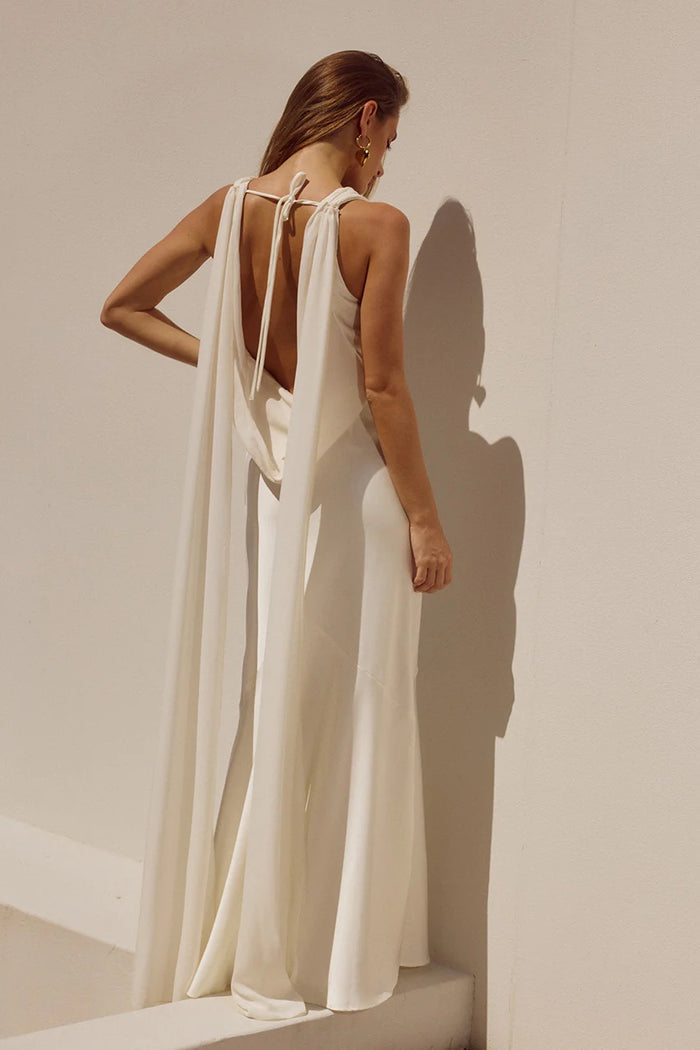 Woman wearing a flowing white dress against a neutral background