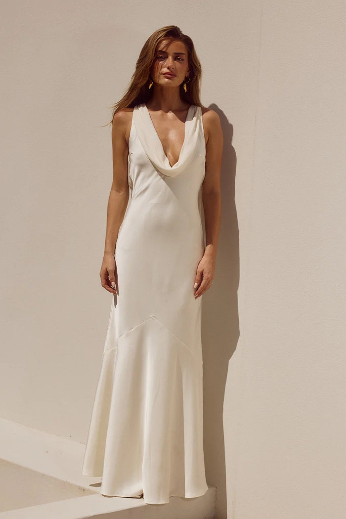 Woman wearing a white sleeveless dress against a beige background