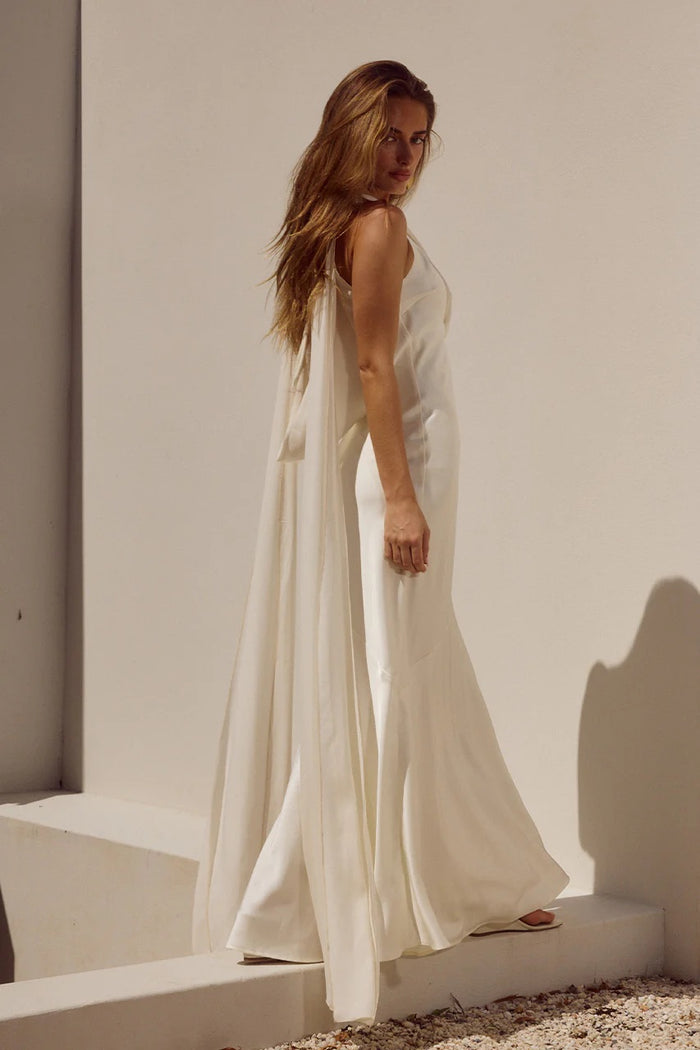 Woman in a white dress standing against a white wall