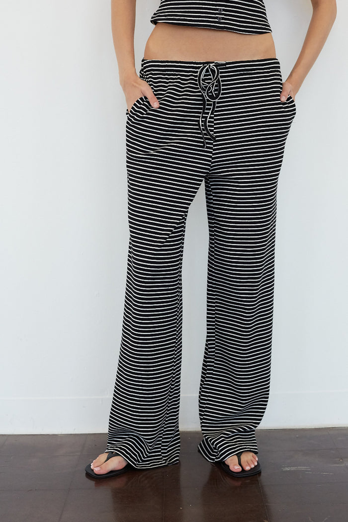 Black and white horizontally striped wide-leg pants with a drawstring waist, modeled with a matching striped crop top against a white wall.