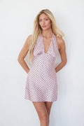 pink-image | Woman wearing a pink polka dot dress against a white background