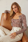 Model sitting wearing a mesh zebra top
