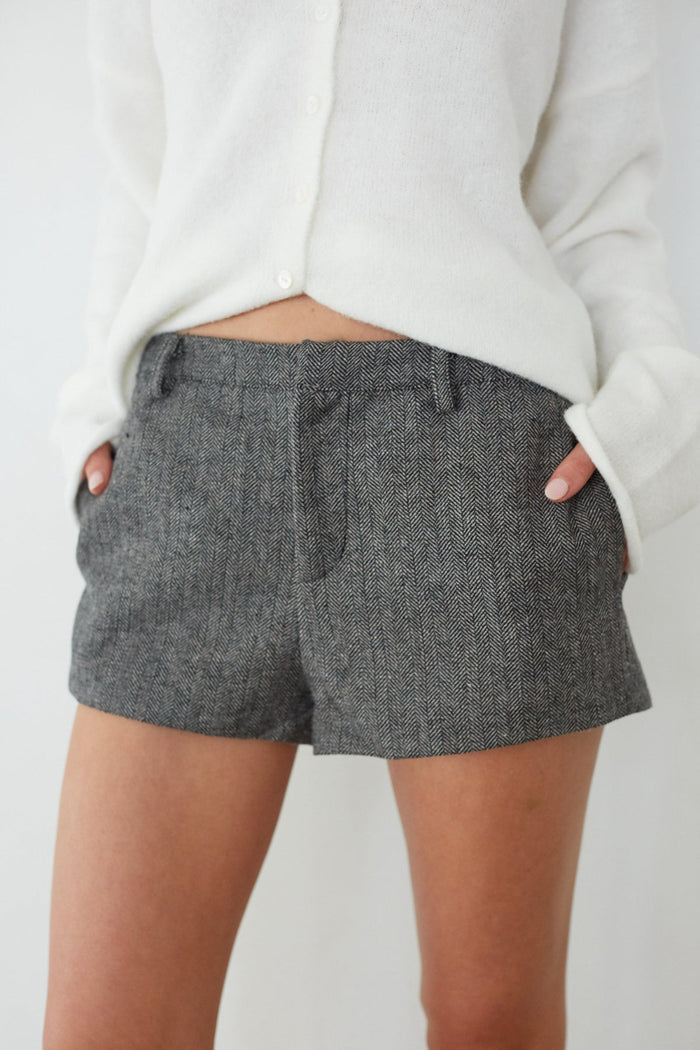 Person wearing gray shorts with a plain background