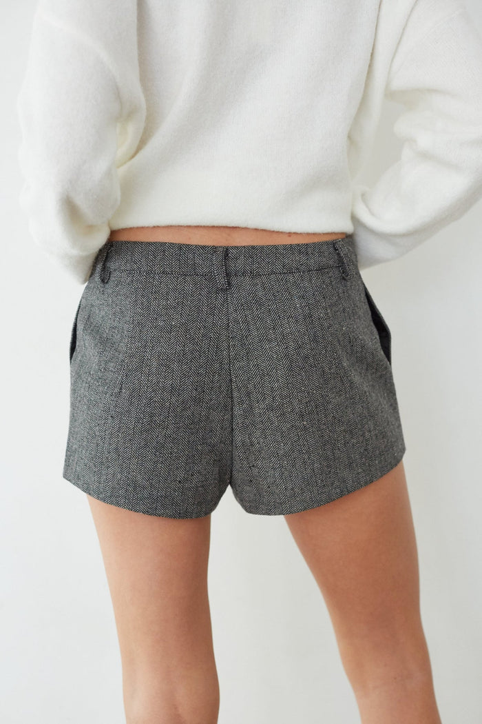 Person wearing gray houndstooth shorts with a white background