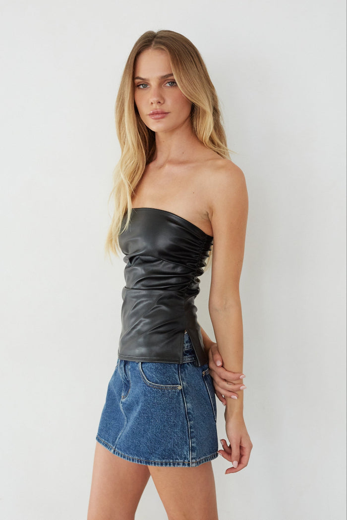 Woman wearing a black strapless top and denim skirt against a white background