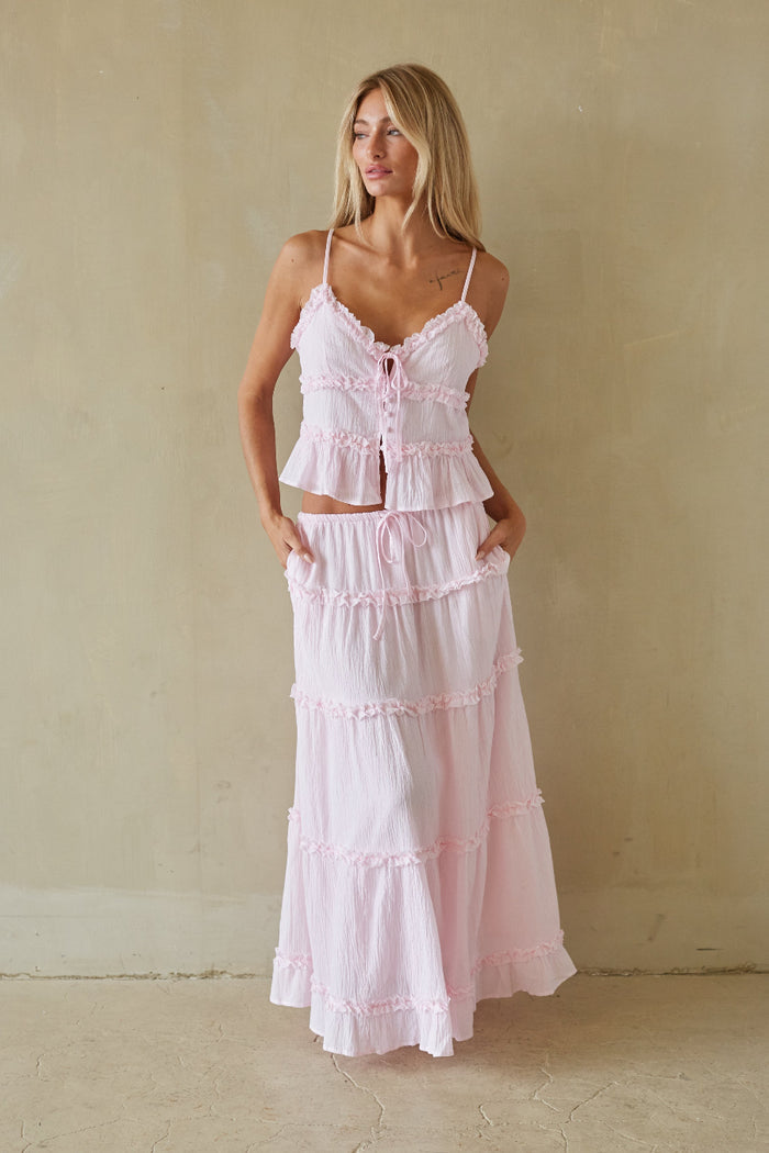 Woman wearing a pink tiered dress against a plain background