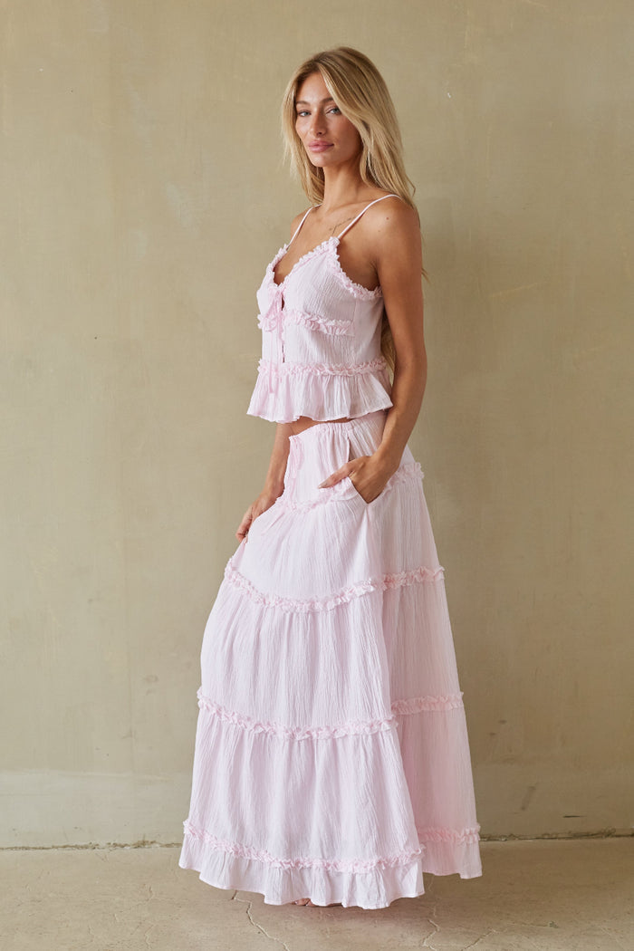 Woman wearing a pink tiered dress against a beige wall