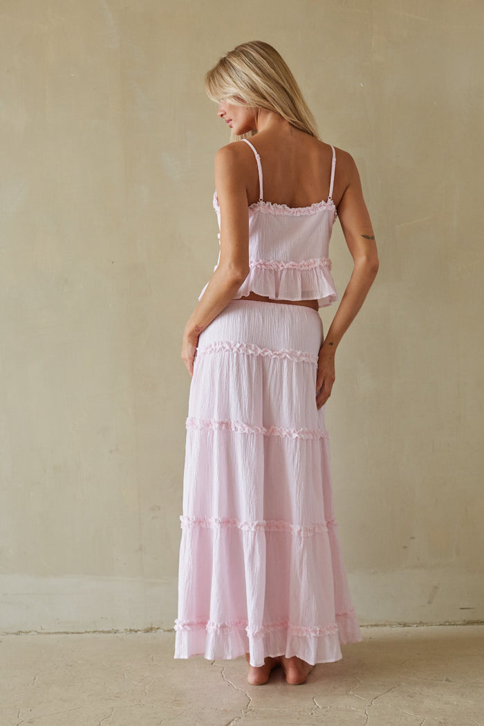 Woman wearing a pink tiered dress against a plain background