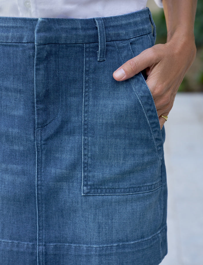 Close-up of a person wearing a blue denim skirt with a blurred background