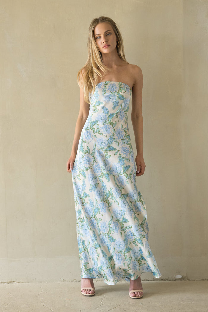 Woman wearing a strapless floral dress against a plain background