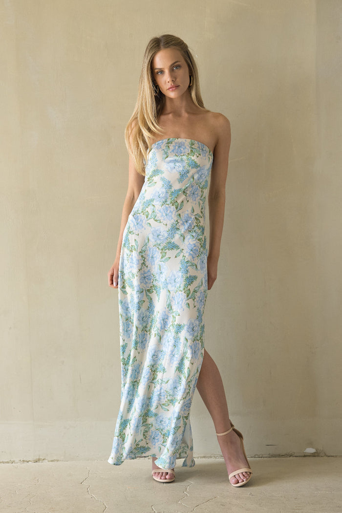 Woman wearing a floral strapless dress against a plain background