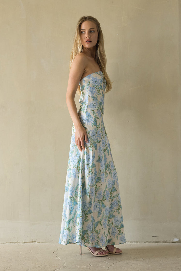 Woman wearing a floral strapless dress against a plain background
