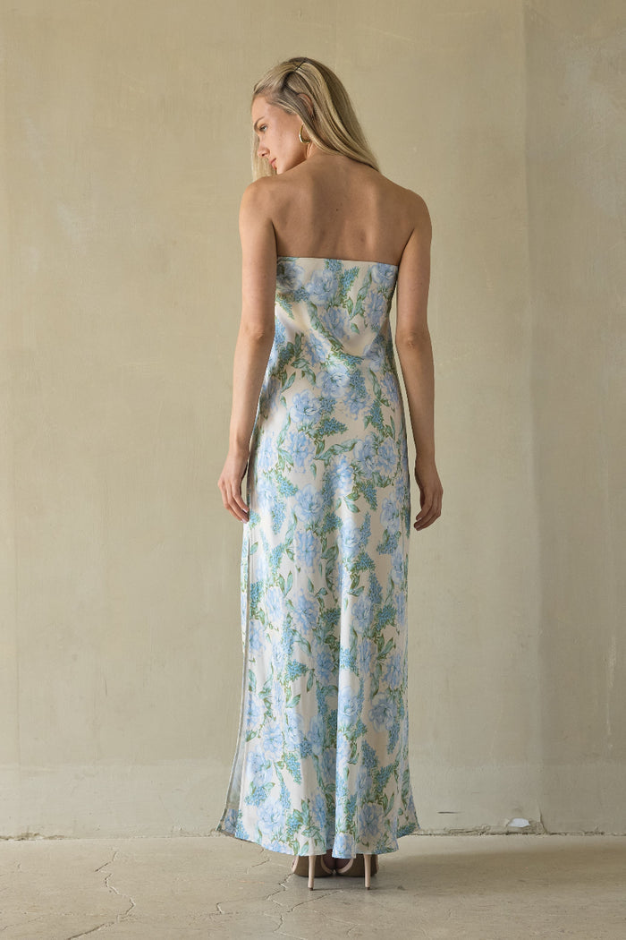 Woman wearing a strapless floral dress against a plain background