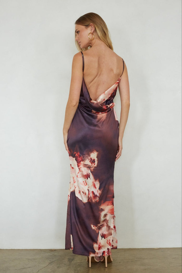 Woman wearing a floral dress with a backless design on a plain background