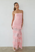 pink-image | Woman wearing a pink strapless dress with ruffled layers against a plain background