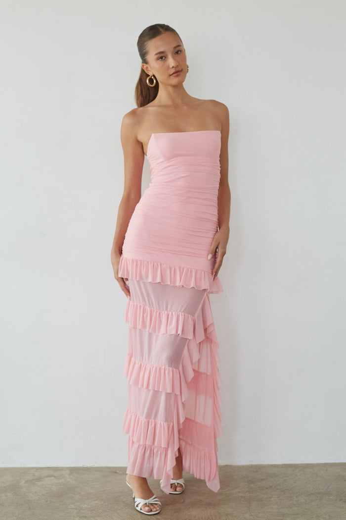 pink-image | Woman wearing a pink strapless dress with ruffled layers against a plain background
