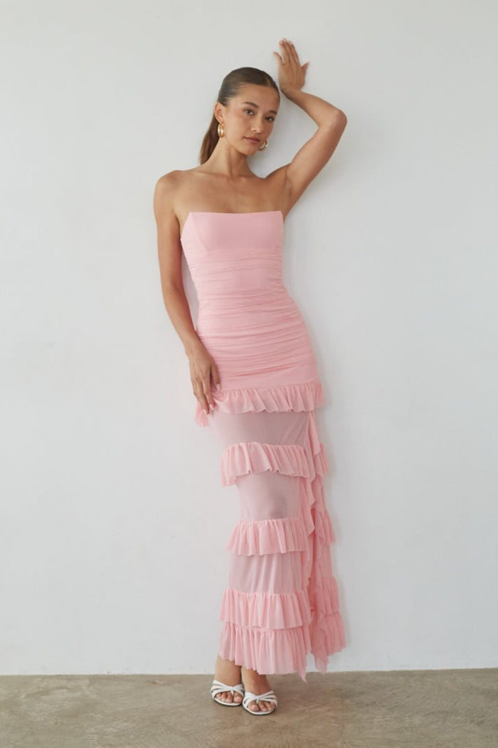 Woman wearing a pink strapless dress with ruffled layers against a plain background