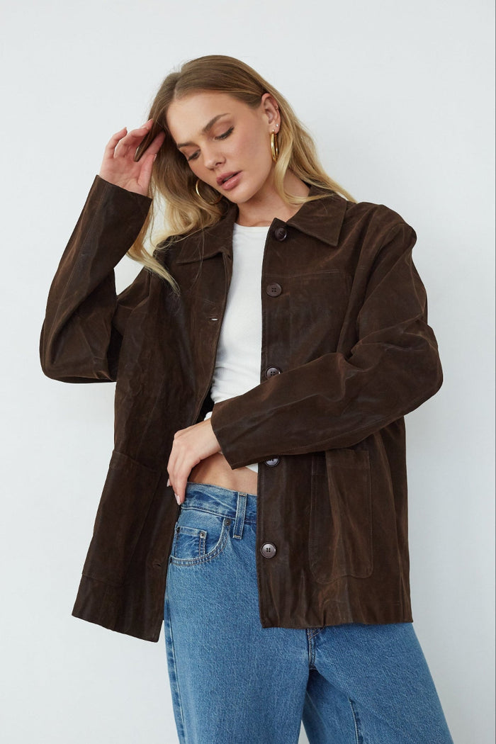 Woman wearing a brown jacket and blue jeans against a white background