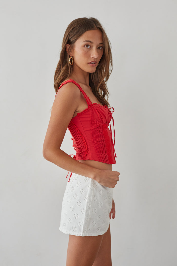 Side-image | Eyelet Lace Mini Skort | side view highlighting the fitted lace-up top and flared eyelet lace mini skort.
