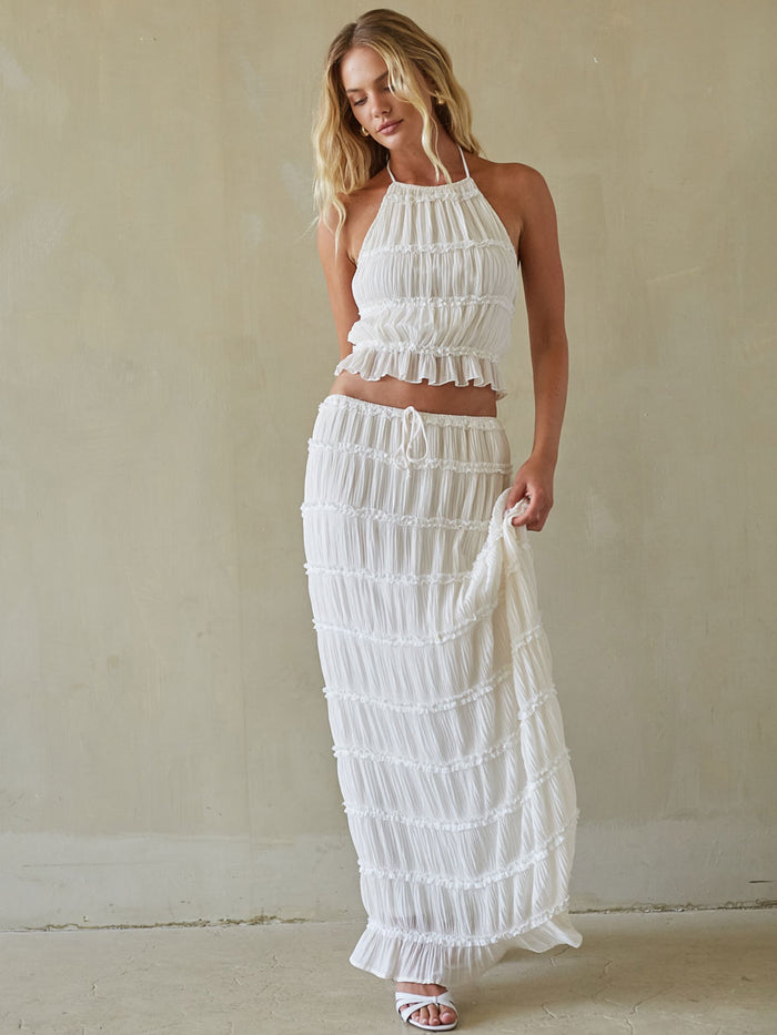 white-image | Woman wearing a white ruffled outfit against a plain background