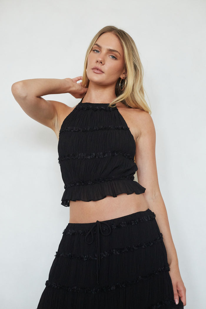 Woman wearing a black ruffled outfit against a white background