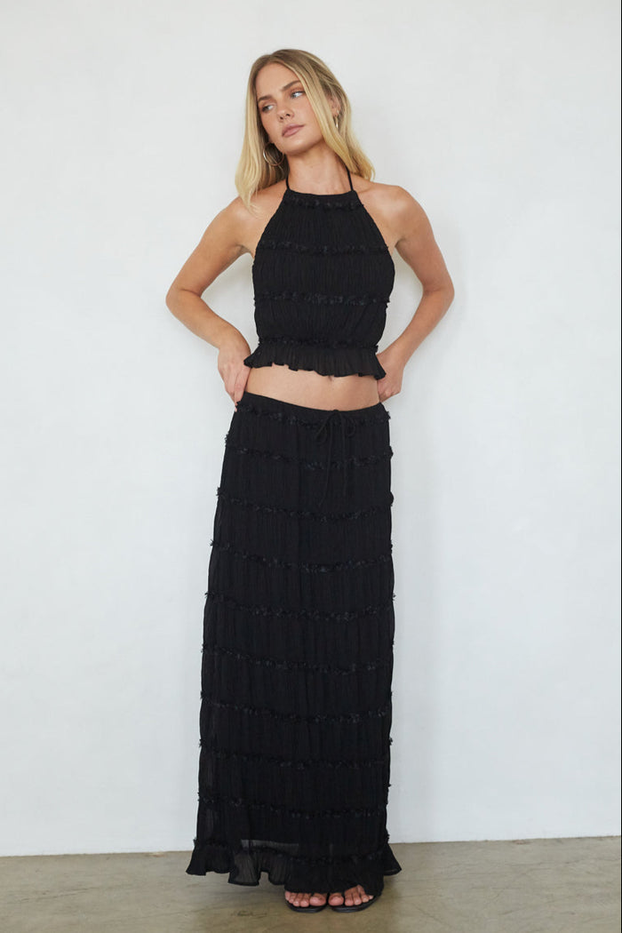 Woman wearing a black halter top and long skirt against a white background