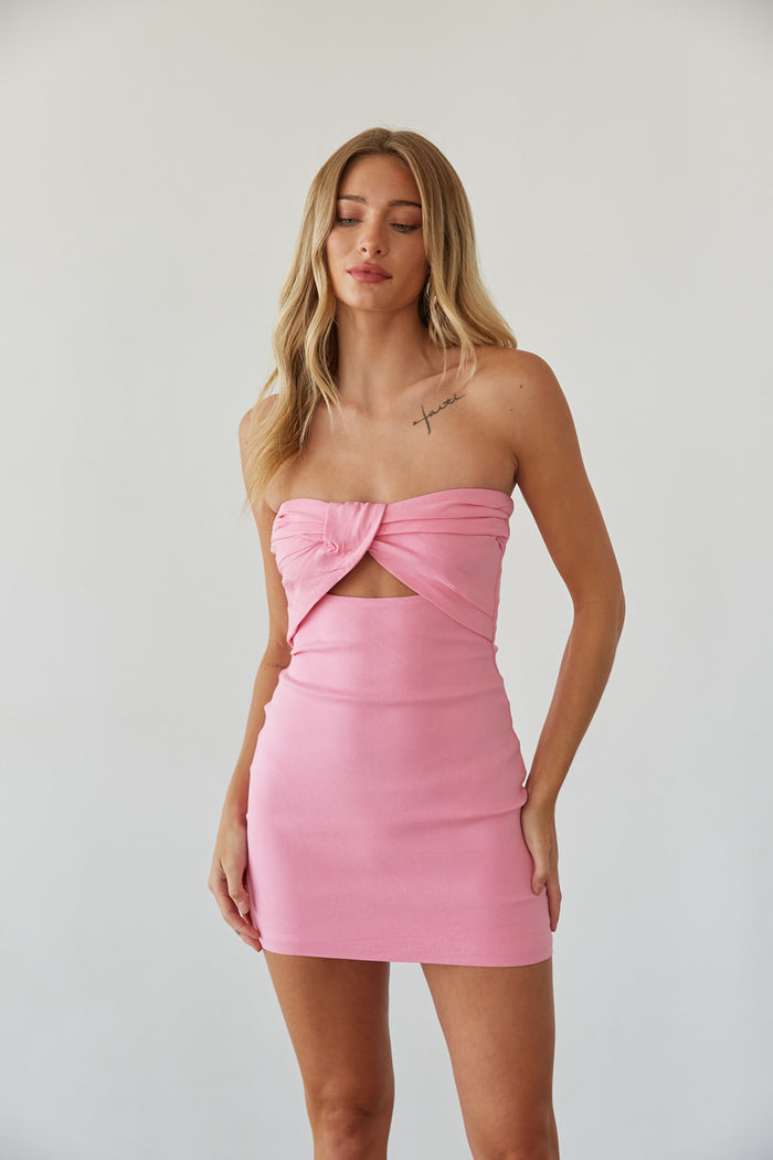 A woman in a strapless pink bodycon mini dress from American Threads, perfect for homecoming or formal events.