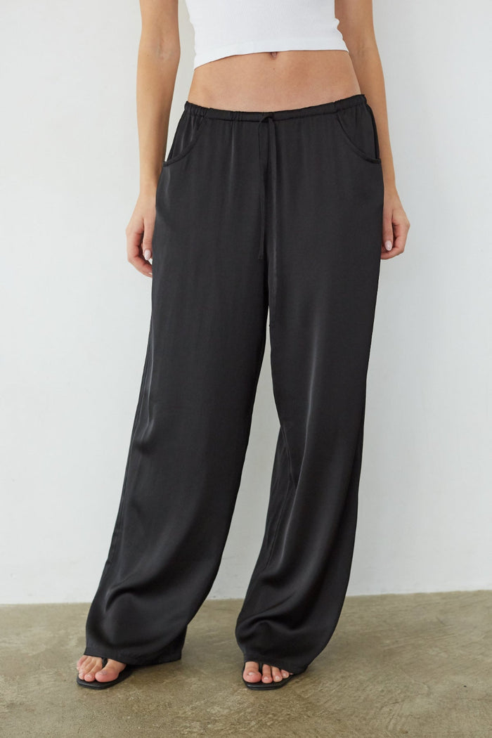 Person wearing black wide-leg pants against a white background