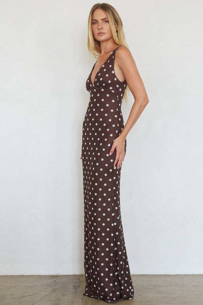 Woman wearing a brown dress with white polka dots against a white background
