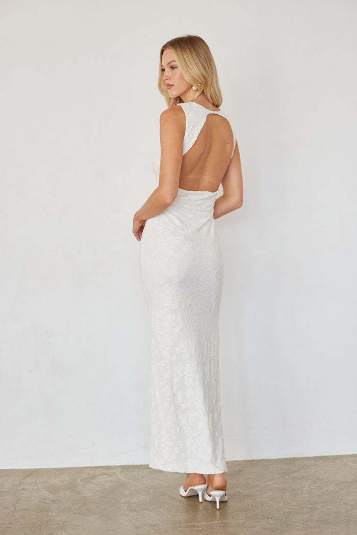 Woman wearing a white dress with an open back against a plain background