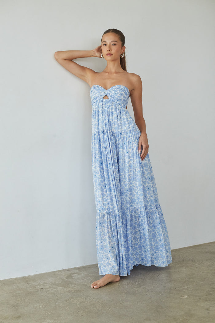 Woman wearing a blue floral strapless dress against a plain background