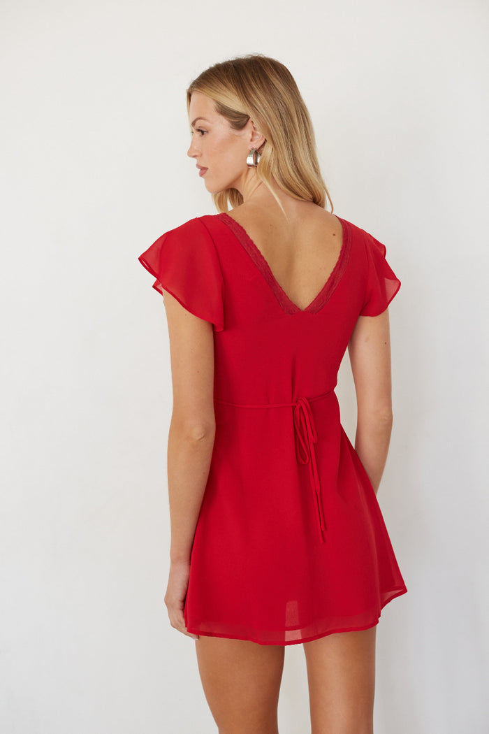 Woman wearing a red dress with ruffled sleeves on a white background