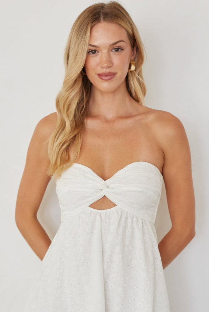 Woman wearing a white strapless dress against a plain background