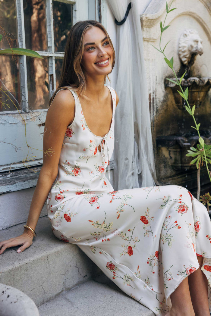 Woman in a floral dress sitting outdoors with a fountain in the background