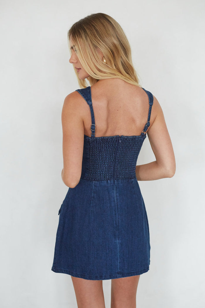 Woman wearing a blue denim dress against a white background