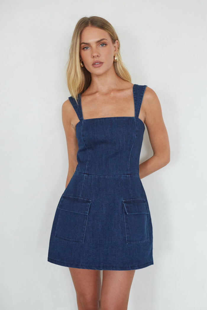 Woman wearing a blue denim dress against a white background