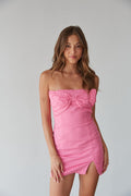 A female in a pink strapless mini dress with bow detail, perfect for hoco dresses or unique homecoming styles.