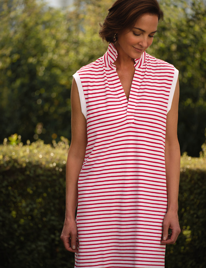Woman wearing a red and white striped dress outdoors with greenery in the background