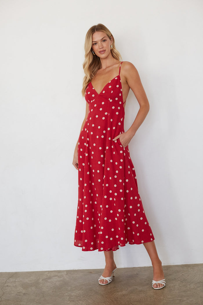 Woman wearing a red polka dot dress against a white background