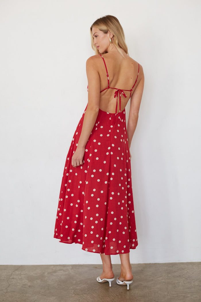 Woman wearing a red polka dot dress against a white background
