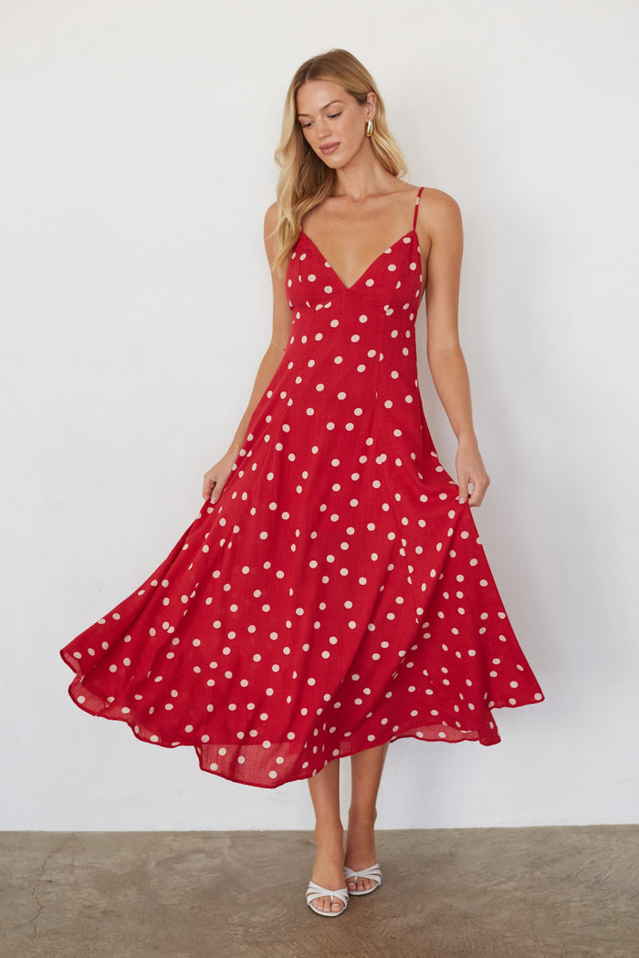 Woman wearing a red polka dot dress against a white background
