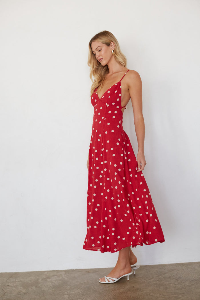 Woman wearing a red polka dot dress against a white background