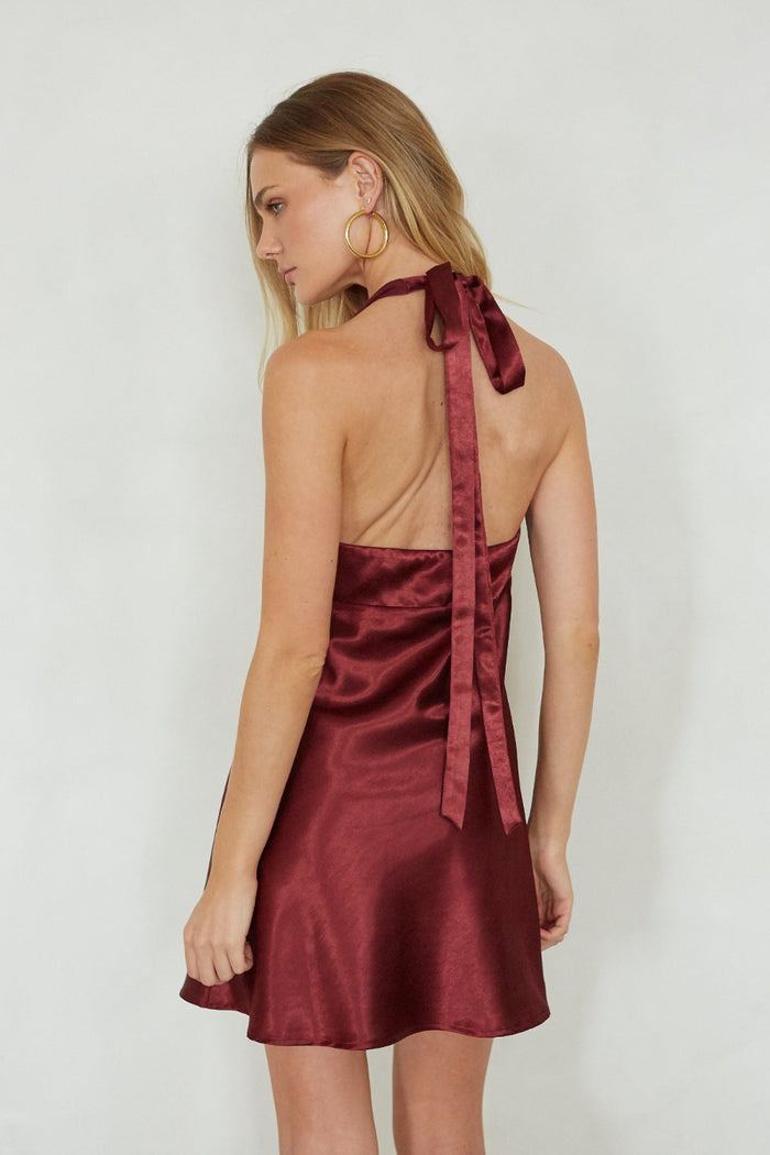 Woman wearing a burgundy satin dress with a white background
