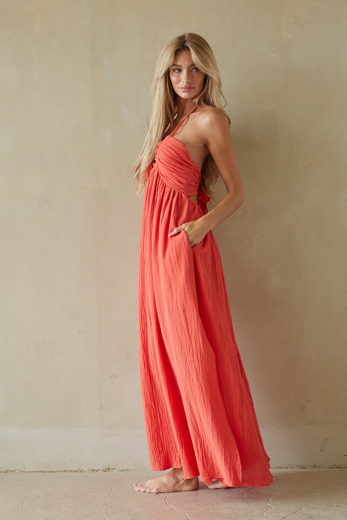 Woman wearing a coral dress against a beige wall