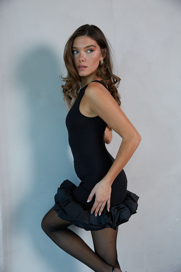 Side-image | Boatneck Bubble Bodycon Mini Dress | side view showing the puffed, bubble hem of the dress and the snug fit.