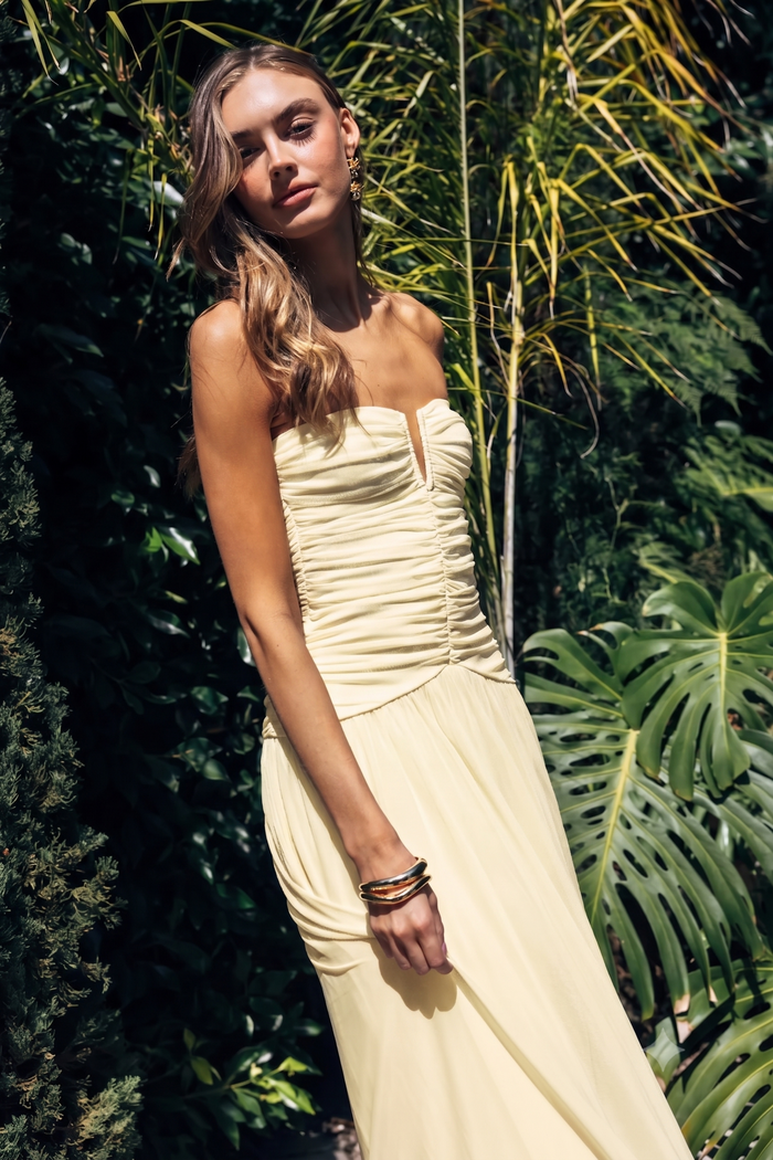 yellow-image | Woman in a strapless yellow dress standing among tropical plants