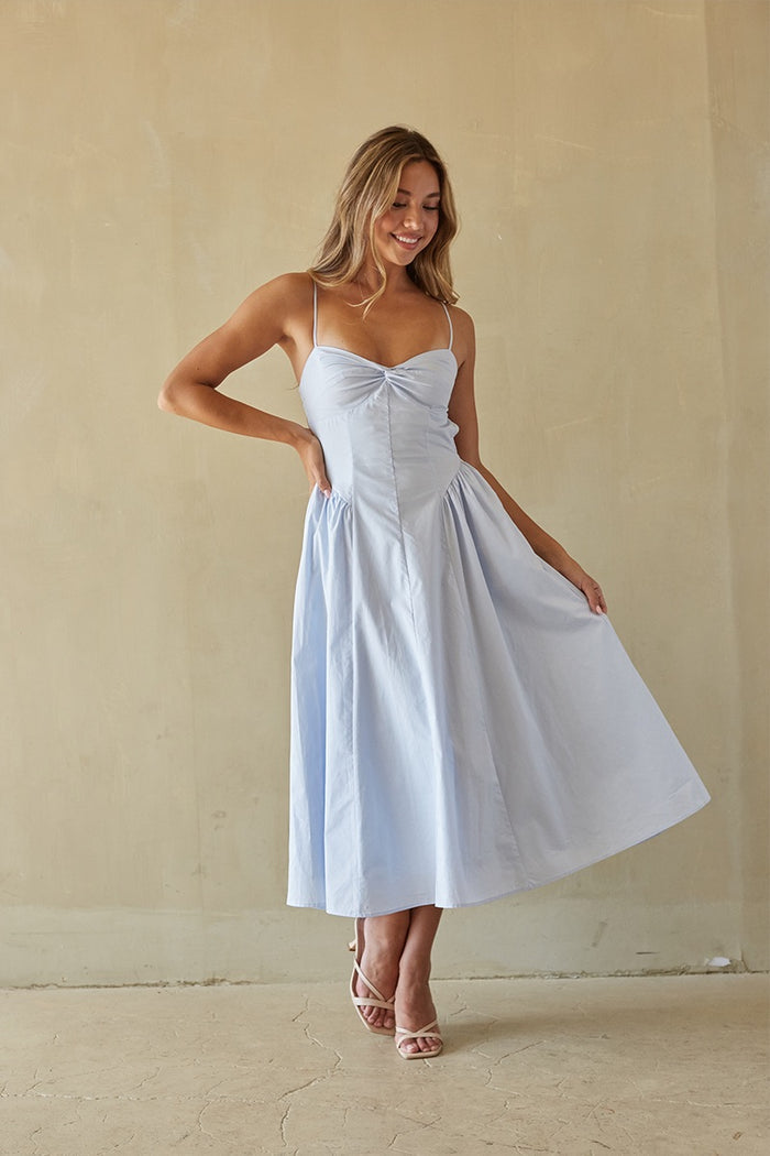 blue-image | Woman wearing a light blue dress against a beige background